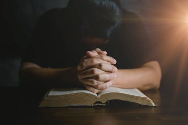 Dua eden kişi siyah arka planda. Hıristiyan katolik kadın kilisede karanlıkta Tanrı 'ya dua ediyor. Kız İsa 'ya inanıyor ve inanıyor. İsa dini ve Hıristiyanlık ibadeti veya dua kavramı.