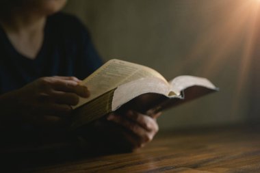 Dua eden kişi siyah arka planda. Hıristiyan katolik kadın kilisede karanlıkta Tanrı 'ya dua ediyor. Kız İsa 'ya inanıyor ve inanıyor. İsa dini ve Hıristiyanlık ibadeti veya dua kavramı.