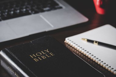 Siyah ahşap arka planda eğitim için kâğıt içeren kutsal İncil kitabı. Protestan inancı olan Hıristiyan Katolik kilisede dua ediyor. İnanç, Tanrı ve din hakkında bilgi edinme kavramı..