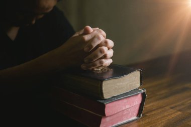 Dua eden kişi siyah arka planda. Hıristiyan katolik kadın kilisede karanlıkta Tanrı 'ya dua ediyor. Kız İsa 'ya inanıyor ve inanıyor. İsa dini ve Hıristiyanlık ibadeti veya dua kavramı.