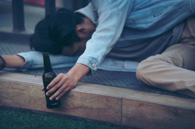 Partiden sonra. Sarhoş sakallı genç adam kaldırımda uzanıyor ve çok fazla bira içtikten sonra uyuyor..