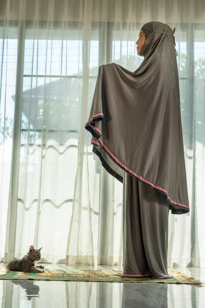 Evdeki oturma odasında dua eden Müslüman bir kadın. Din Görev Günlüğü. İnsanların silueti