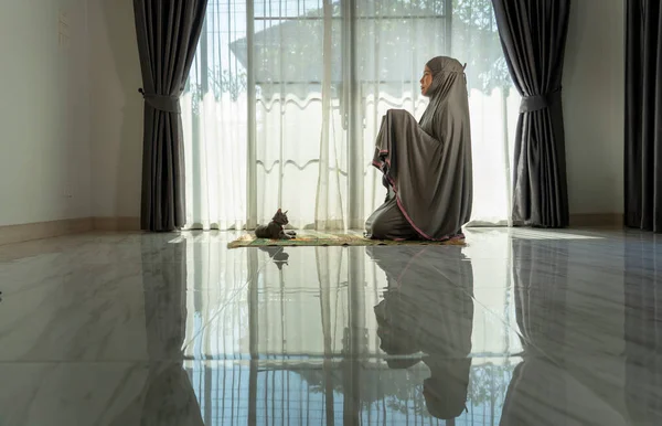 Evdeki oturma odasında dua eden Müslüman bir kadın. Din Görev Günlüğü. İnsanların silueti