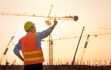 Mühendis İnşaat Mühendisi Teknisyeni İş Ekibi yeni inşaat alanında planı tartıştı. Otoyol inşaatında yol yapım makineleri. Yüksek zemin ağır sanayi ve güvenlik kavramı.