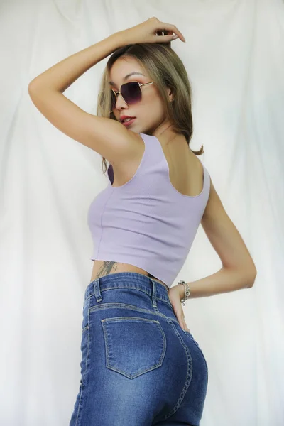 Dövmeli güzel bir moda kızı. Kırpık Üstlü İnce Kadın 'ın portresi. Güzel Kadın Gök mavisi ile duruyor En iyi moda kataloğu konsepti.