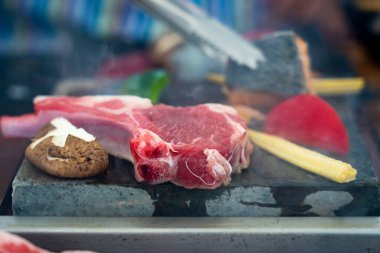 Izgara biftekle baharatı karıştırılmış sıcak taşın üstünde. Asya yemeği konsepti. Sıcak taşın üstünde sıcak biftek..