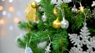 Kadın Noel ağacını süsleyerek süslüyor. Noel ağacı, altın süs ve eller yakın plan