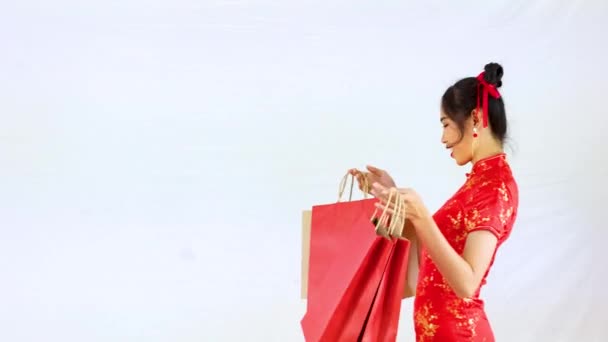 4K视频亚洲女人身穿红色传统东方服装 手持白色背景的购物袋 中国新年购物观念风格 — 图库视频影像