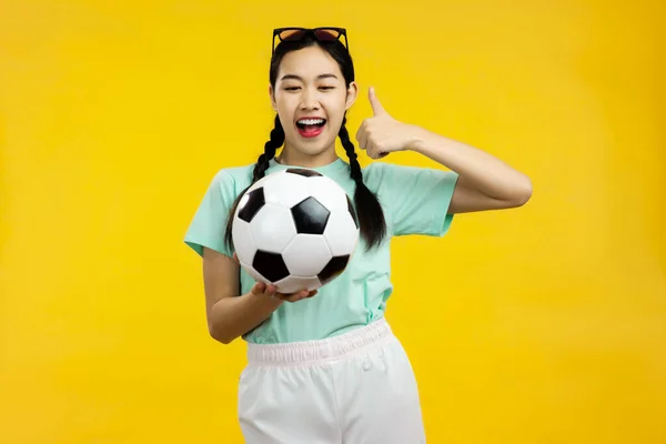 Portret Azjatki Trzymającej Piłkę Nożną Pokazującej Kciuk Górę Odizolowane Żółte — Zdjęcie stockowe