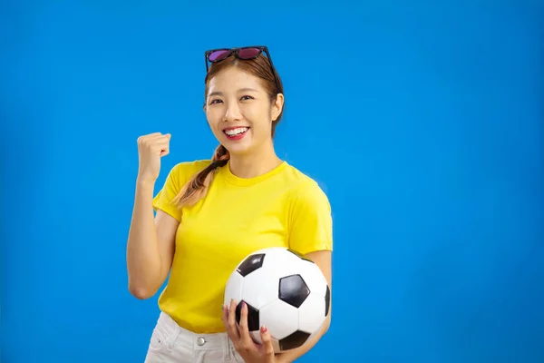 アジアの若い女性は 孤立した青の背景にサッカーボールを保持し 陽気な肯定的な感情 スポーツの概念 — ストック写真