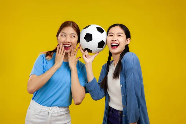 Dwie Azjatki Młoda Kobieta Odizolowanym Żółtym Tle Trzyma Piłkę Nożną — Zdjęcie stockowe