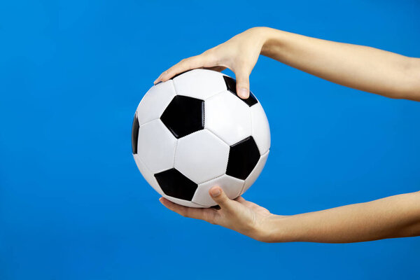 Female hand holding soccer ball isolated blue wall background, spaort concept
