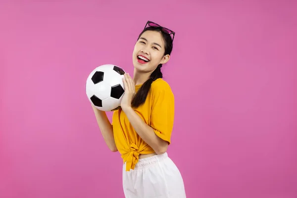 幸せなアジアの女の子サッカーファン以上隔離されたピンクの背景保持サッカーボールとカメラを見て スポーツの概念 — ストック写真