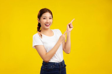 Asyalı bir kadının izole edilmiş sarı arka plan, moda ve yaşam tarzı kavramına işaret ettiği fotoğraf.