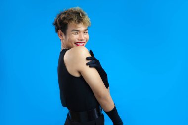 Kırmızı dudak nemlendiricisi ve siyah kolsuz tişörtü olan mutlu, hoş bir gay. Transseksüel erkek, mavi arka plan izole edilmiş. LGBTQ + kavramları