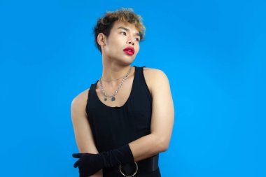 Kırmızı dudak nemlendiricisi ve siyah atletli yakışıklı bir eşcinsel portresi. Transseksüel erkek, mavi arka plan izole edilmiş. LGBTQ + kavramları