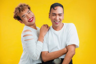 Sarı arka planda gülümseyen neşeli erkek çift. İki Asyalı gay yan yana duruyor ve kameraya bakıyor..