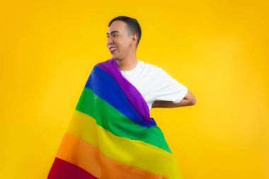 LGBT gökkuşağı bayrağı omuz izole sarı arka planda mutlu gay hareketi. Eşcinsel gurur bayrağı taşıyan adam