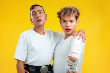 İki Asyalı eşcinsel yan yana duruyor ve sarı arka plan görüntülerine bakıyor. lgbtq ve lgbtq + kavramları