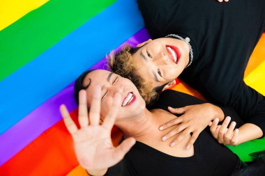 Happy asian gay couple lay down on pride flag rainbow color background. lgbtq and lgbtq+ concepts clipart