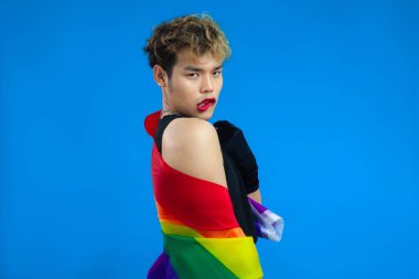 Gökkuşağı bayraklı Asyalı gay stüdyo portresi mavi arkaplanı izole etti. lgbtq ve lgbtq + kavramları