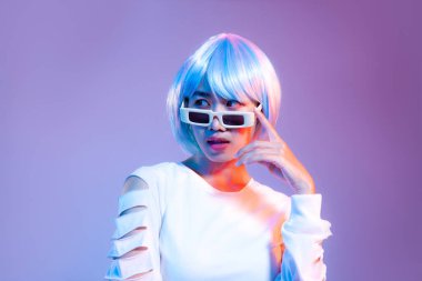 Mor perde arkasında eski güneş gözlüğü takan beyaz giysili genç Asyalı kadın..