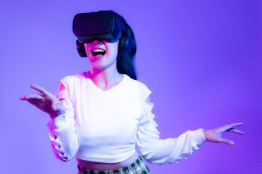 Metaverse konsept, beyaz moda sweatshirt giyen Asyalı genç kız VR kulaklık takıyor ve online oyun mor arka planına dokunuyor..