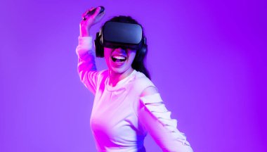Metaverse konsept, beyaz moda sweatshirt giyen Asyalı genç bir kız VR kulaklık takıyor çevrimiçi oyun oynuyor mor arka plan izole edilmiş.