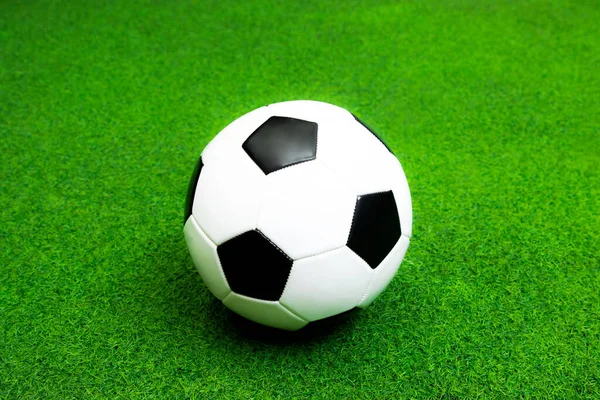 Soccer ball black and white leather on the green artificial grass field for sport background.