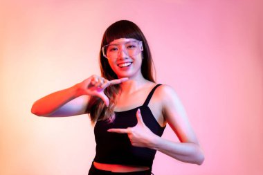 Young asian woman long hair in black tank top posing showing and presenting on the red pastel background.	