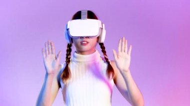 Metaverse concept, young asian woman wearing white vr headset touching isolated purple neon background. 4K video asian girl futuristic style gamer.