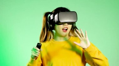 Metaverse concept, amazed young asian woman wearing black vr headset touching on the green neon screen background. 4K video asian girl futuristic style gamer.