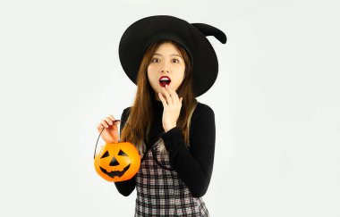 Happy halloween, young asian woman in black costume wearing witch hat carrying lantern pumkin posing exciting on white background.