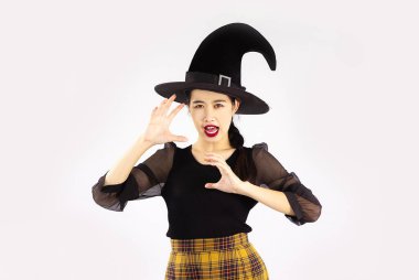 Young asian woman wearing black witch hat and black costume to celebrate halloween on white background.