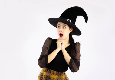 Young asian woman wearing witch hat and black costume and posing scary to celebrate halloween on white background.