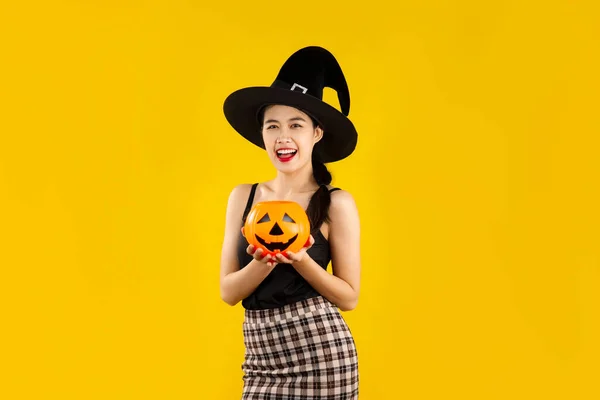 若いですアジアの女性で黒タンクトップ身に着けています魔女帽子Posing上の黄色の背景のためにザハロウィーンの概念 — ストック写真