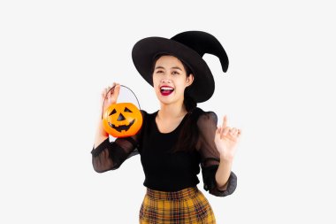 Cadılar Bayramı teması, siyah cadılar bayramı kostümü giymiş, elinde turuncu balkabağı kovası olan, beyaz arka planı gösteren genç ve güzel Asyalı bir kadın..