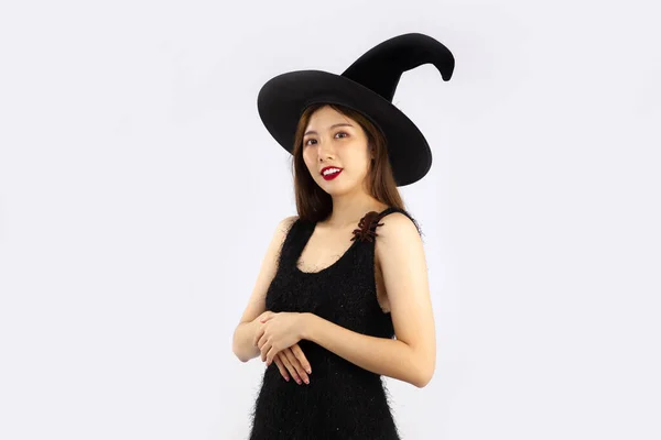 ハロウィンテーマ 若いです可愛いですアジアの女性で黒のドレス身に着けている魔女帽子ポージング上の白い背景 — ストック写真