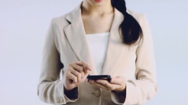 4K video, bej renkli ceketli genç iş kadını akıllı telefon ekranına dokunuyor beyaz arka plan.