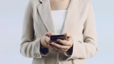 4K videosunda bej renkli ceketli genç Asyalı kadının akıllı telefon mesajları ve internet üzerinden beyaz arka plan alışverişi yaptığı videoyu kapat..