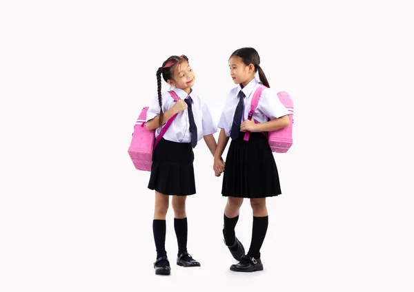 白壁の背景に立つピンクのバッグパックで制服姿の小中学生 小学生に戻る — ストック写真