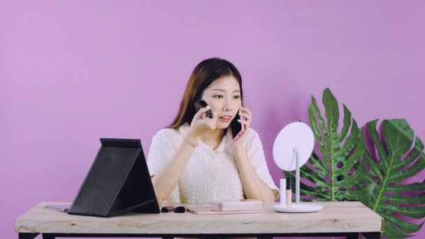 视频4K 年轻的亚洲女人穿着白衬衫 坐着化妆 同时在粉红的背景墙上用月台相机记录她的博客 — 图库视频影像