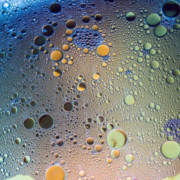 Su üzerinde mavi ve sarı yağ kabarcıkları, soyut arkaplan
