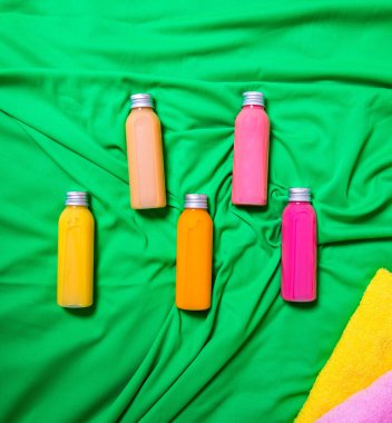 Vücut bakımı için spa seti, spa prosedürleri için jel şişeleri yeşil arka planda banyo havlularının üzerinde yatar, kopyalama alanı, düz döşeme, şablon