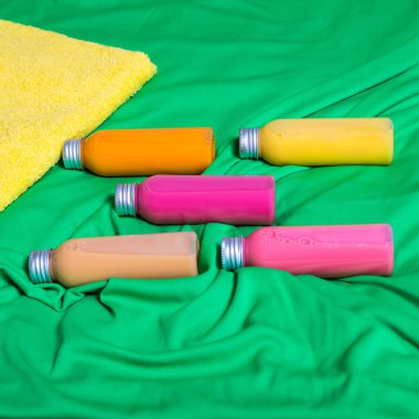 Vücut bakımı için spa seti, spa prosedürleri için jel şişeleri yeşil arka planda banyo havlularının üzerinde yatar, kopyalama alanı, düz döşeme, şablon