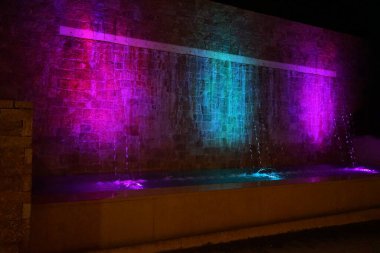 Büyük şehir mimarisi. Atina Caddesi, Kolympia, Rodos, Yunanistan 'da akşam saatlerinde fıskiye aydınlandı 