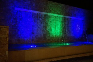 Büyük şehir mimarisi. Atina Caddesi, Kolympia, Rodos, Yunanistan 'da akşam saatlerinde fıskiye aydınlandı 