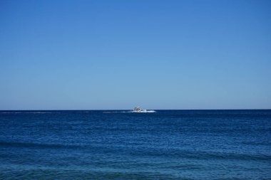 Akdeniz 'de Rodos adasının açığında bir motorlu tekne içinde insanların bulunduğu şişme bir salı çekiyor. Kolympia, Yunanistan  