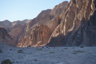 Turistler ATV ile Dahab 'ın pitoresk yerlerinden geçiyorlar. Arazi aracı ATV (ayrıca hafif hizmet aracı LUV, dörtlü bisiklet ya da kısaca Dörtlü bisiklet olarak da bilinir), düşük basınçlı lastikler üzerinde seyahat eden bir araçtır. Dahab, Güney Sina Valiliği, Mısır
