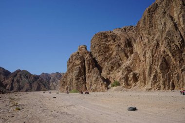 Turistler ATV ile Dahab 'ın pitoresk yerlerinden geçiyorlar. Arazi aracı ATV (ayrıca hafif hizmet aracı LUV, dörtlü bisiklet ya da kısaca kuad olarak da bilinir) bir araçtır. Dahab, Güney Sina Valiliği, Mısır